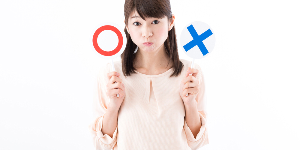 丸とバツの札を持つ女性