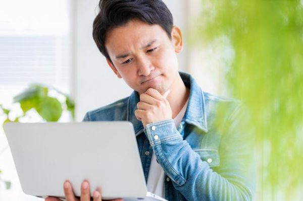 ノートPCを見て首をかしげる男性